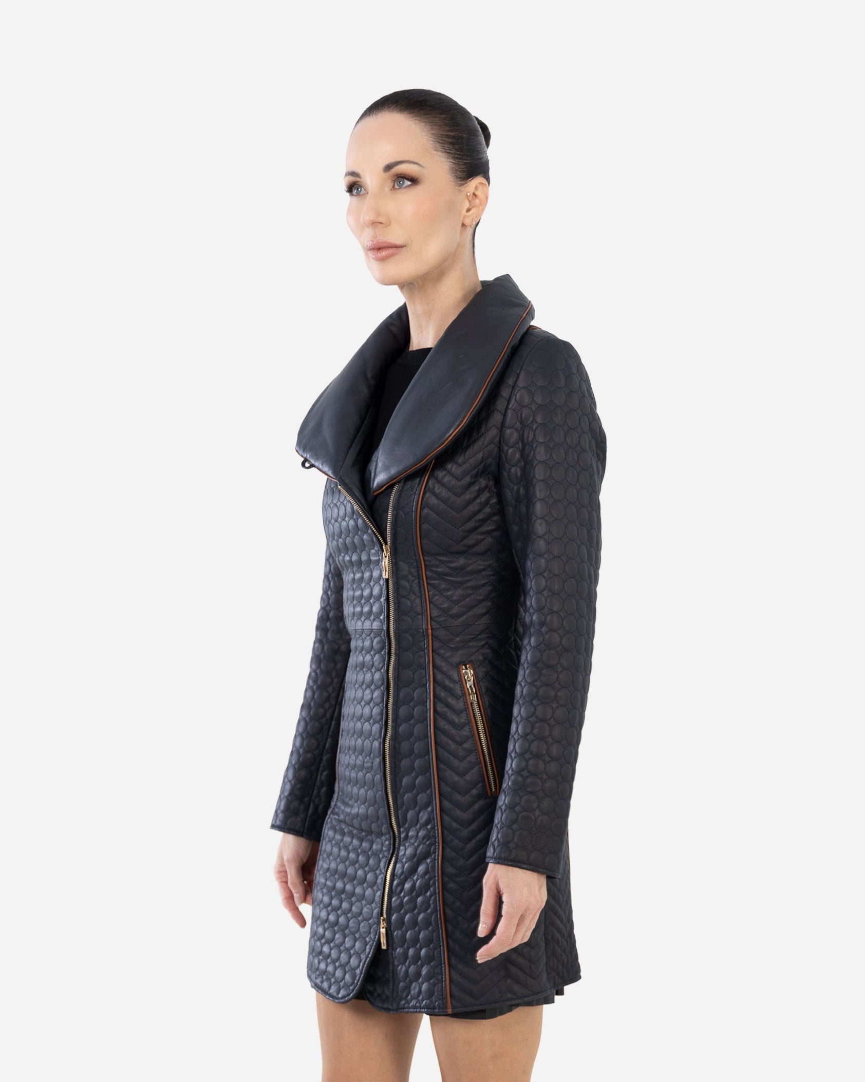 Woman wearing a long, dark quilted coat on a white background